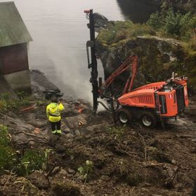 Grunnboremaskin borer i berg ved sjøen